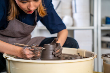 Fototapeta na wymiar Asian woman sculptor artist hands sculpture clay on pottery wheel at ceramic studio. Female craftsman molding raw clay create pottery shapes at workshop. Small business handicraft product concept.