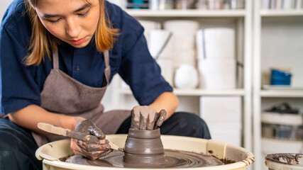 Obraz na płótnie Canvas Asian woman sculptor artist hands sculpture clay on pottery wheel at ceramic studio. Female craftsman molding raw clay create pottery shapes at workshop. Small business handicraft product concept.