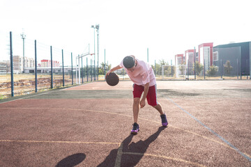 a young male basketball player doing dribble drills on the court outdoors