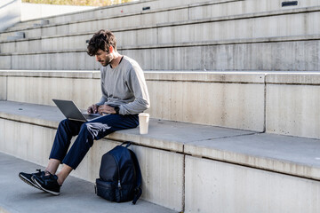 Man sitting on outdoor stairs using laptop