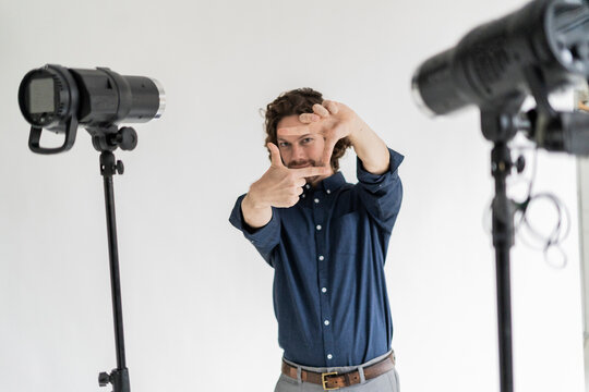 Portrait of a photographer in his studio making a finger frame