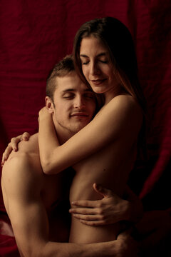 Intimate young couple hugging in front of ruby curtain