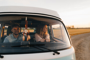 Couple driving camper van on dirt track in rural landscape