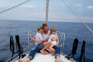 Father with his children sitting on boat deck during sailing trip