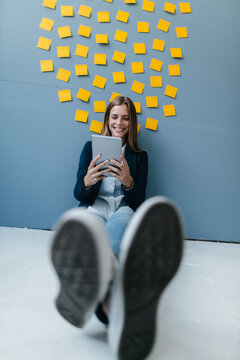 Young businesswoman sitting under data cloud, using digital tablet