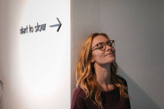 Young woman leaning against a wall with closed eyes