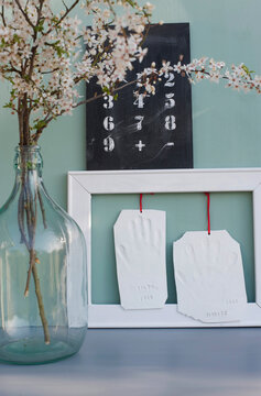 Clay handprints hanging inside picture frame, blackboard with numbers and blossoming blackthorn branches