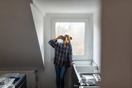 Young woman wearing VR glasses in unfinished kitchen