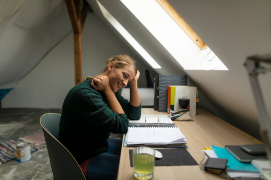 Young woman sitting at desk in attic studying folder