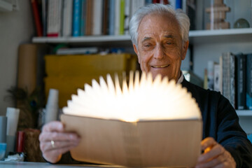 Senior man with glowing book at home