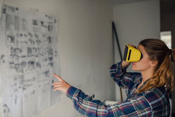 Young woman wearing VR glasses with assembly instructions at the wall