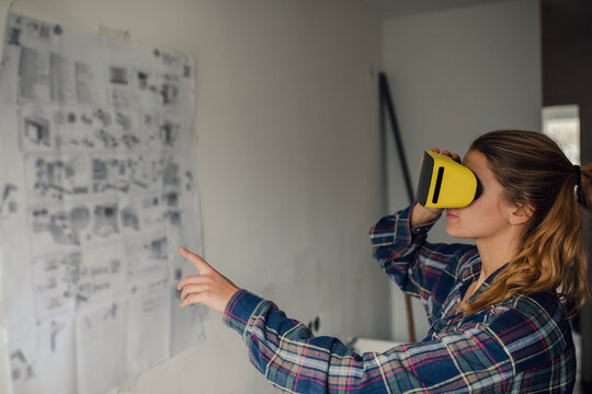 Young woman wearing VR glasses with assembly instructions at the wall