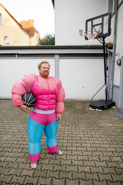 Portrait of a man with basketball wearing pink bodybuilder costume