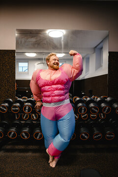 Proud man wearing pink bodybuilder costume flexing his muscles