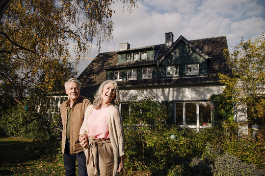 Happy senior couple in garden of their home in autumn