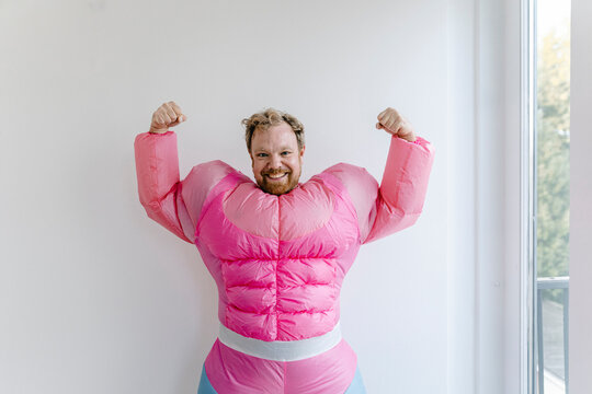 Proud man wearing pink bodybuilder costume flexing his muscles