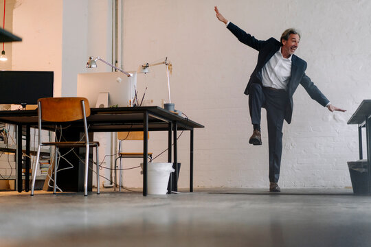 Happy senior businessman doing gymnastics in office - Powered by Adobe