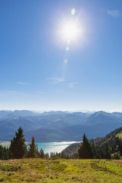 Scenic view of meadow on Salzburger with lake against blue sky on sunny day