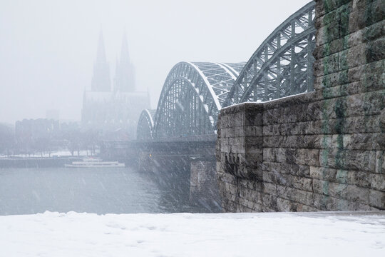 Hohenzollern Bridge over Rhine river by Cologne Cathedral during snowfall in city against sky