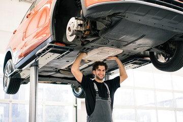 Portrait of a car mechanic in a workshop pretending to lift up a car