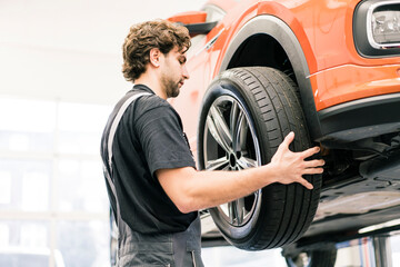 Car mechanic in a workshop changing tire