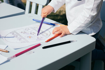 Close-up of toddler coloring Easter egg on a paper