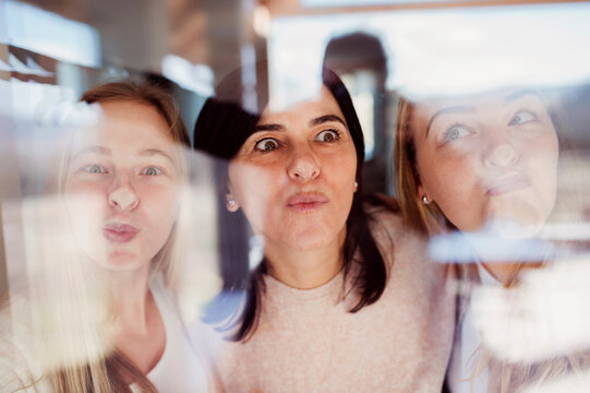 Mother and daughters pressing noses against window pane