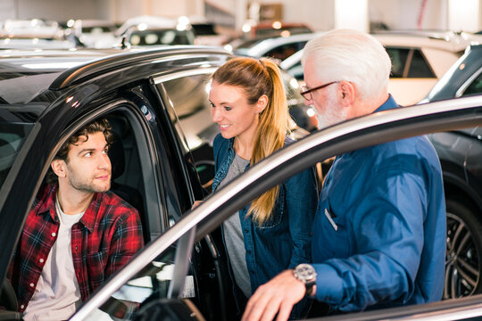 Car dealer showing car to couple in showroom