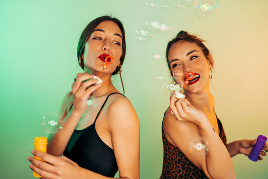 Portrait of two friends blowing soap bubbles