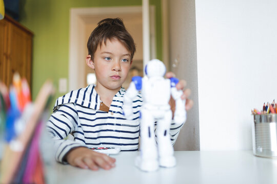 Boy playing with his remote-controlled toy robot at home