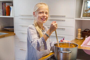 Portrait of happy girl cooking jam at home