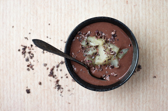Chocolate pudding with pineapple chunks and cacao nibs