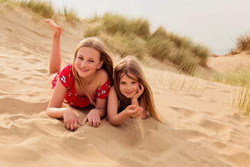 Portrait of two smiling girls lying on the beach