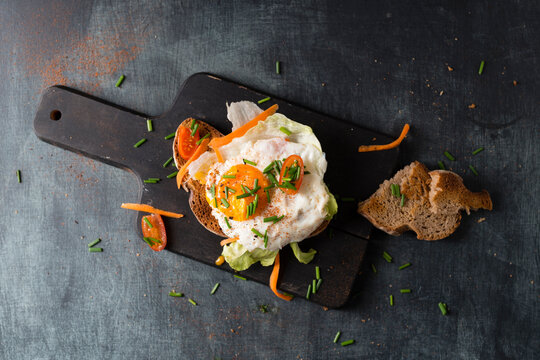 Fried egg with bread and vegetables lying on cutting board
