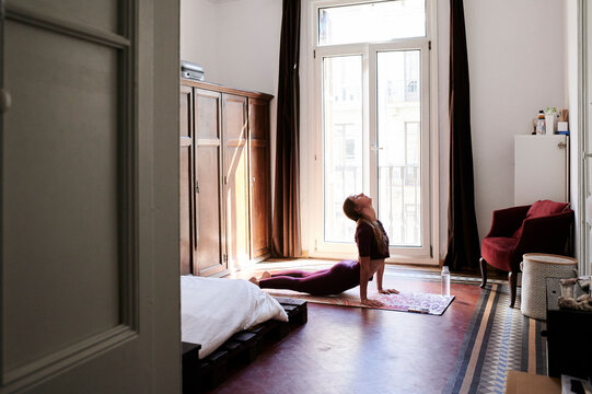 Young brunette woman practising yoga in student dorm