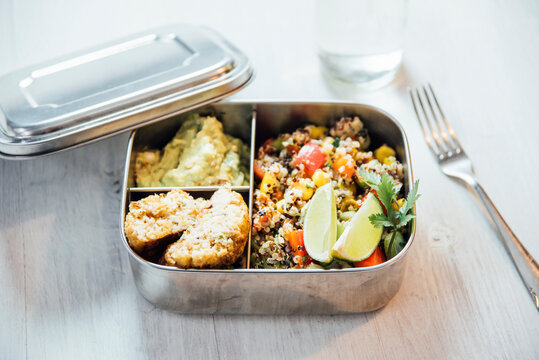 Bento box of quinoa salad with vegetables and lime, avocado cream and cauliflower dumplings