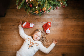 Smiling girl lying under the Christmas tree