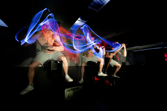 Man practicing sport in dark area surrounded by colored lights