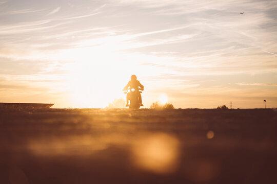 Silhouette of man riding custum motorcycle at sunset