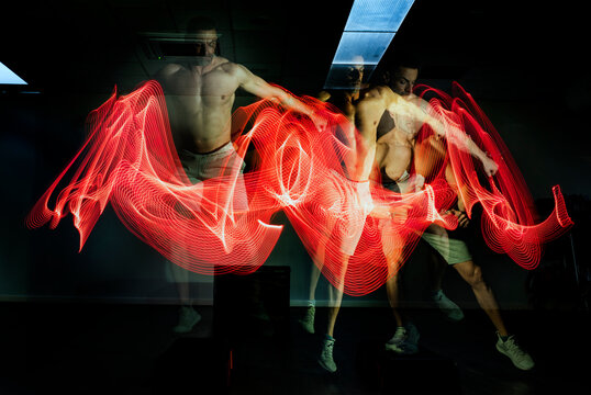 Man practicing sport in dark area surrounded by colored lights