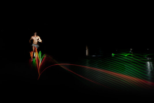 Athlete running in dark area surrounded by colored lights