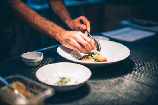 Cook serving food on a plate in the kitchen of a restaurant