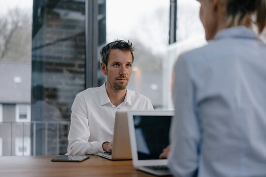 Businessman and woman sitting at desk, working on laptop