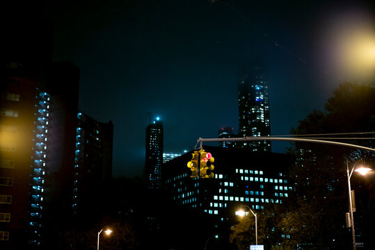 USA, New York, New York City, Stoplight hanging against illuminated skyscrapers at night