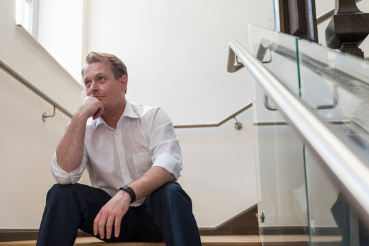 Thoughtful businessman sitting in staircase