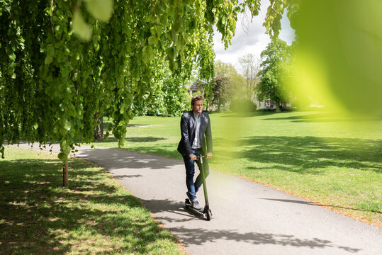 Businessman using E-Scooter in a park
