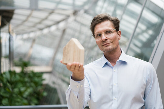 Architect holding wooden house modell, standing in sustainble building