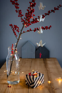 Wrapped present, twig of holly in vase and fairy lights