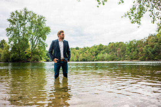 Businessman standing in a lake looking out