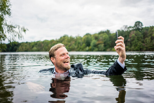 Mad Businessman Holding Cell Phone Inside A Lake